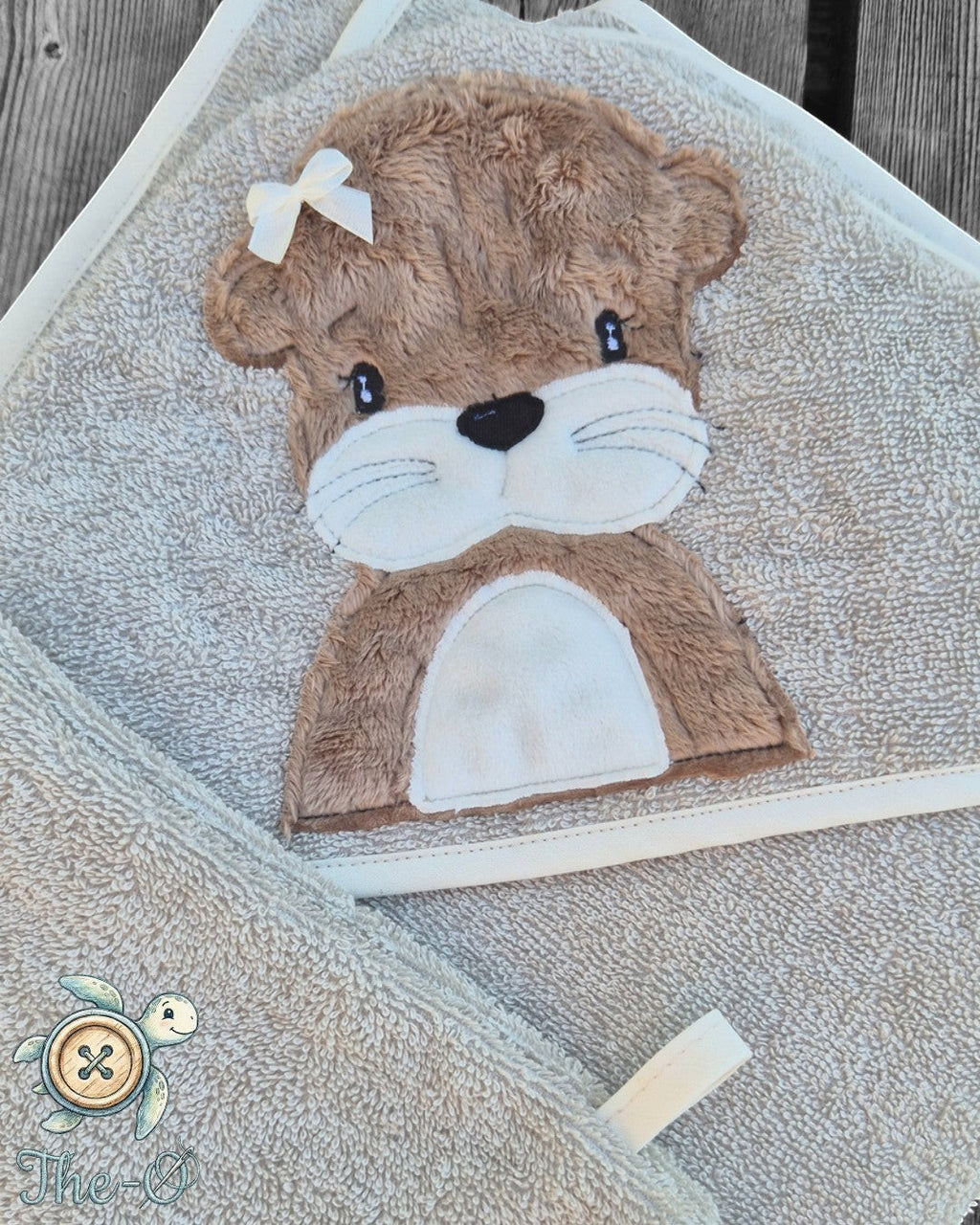 The-O Otter Set bestehend aus beigem Frottee-Handtuch und Waschlappen mit niedlicher Otter-Applikation und Schleife